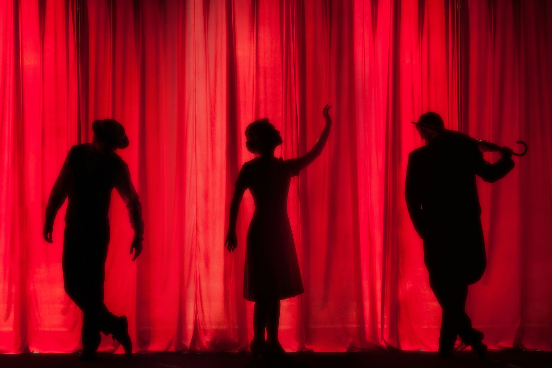 Silhouettes against a red theatre curtain
